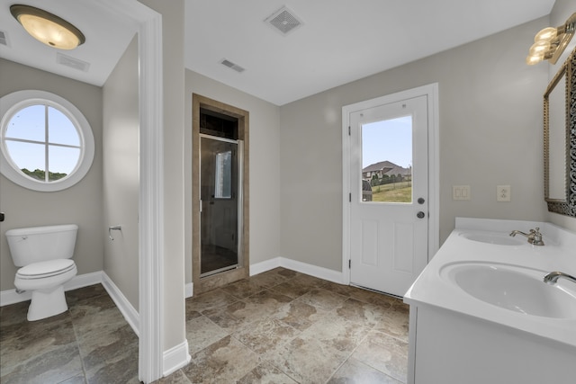 bathroom featuring vanity, toilet, a healthy amount of sunlight, and a shower with door