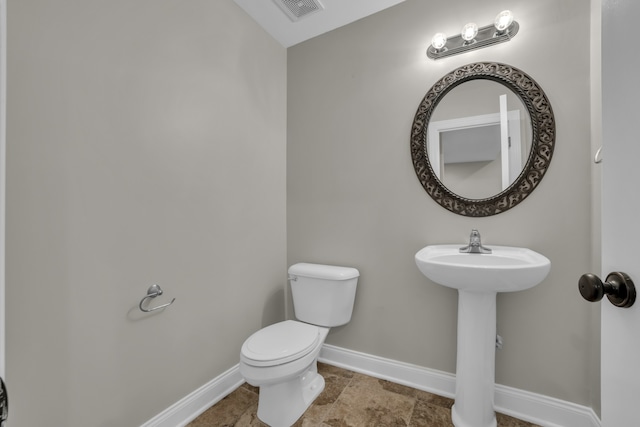 half bathroom featuring toilet, baseboards, and visible vents