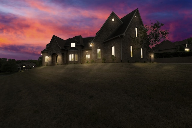 french provincial home featuring stone siding and a yard