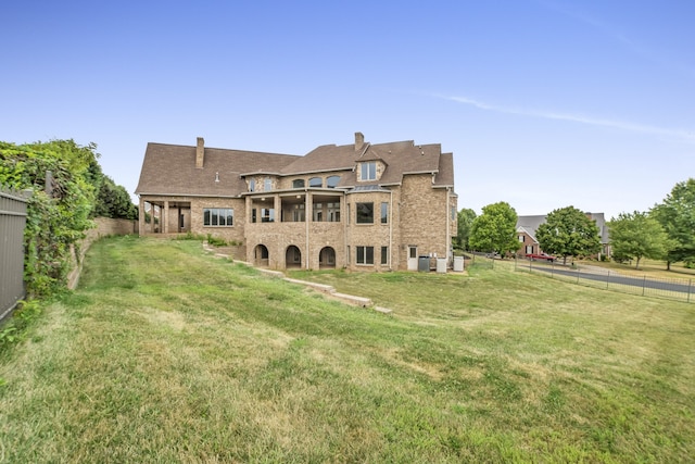 rear view of house with a fenced backyard, a yard, and central air condition unit