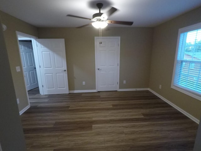 unfurnished bedroom with ceiling fan, baseboards, and dark wood-style flooring