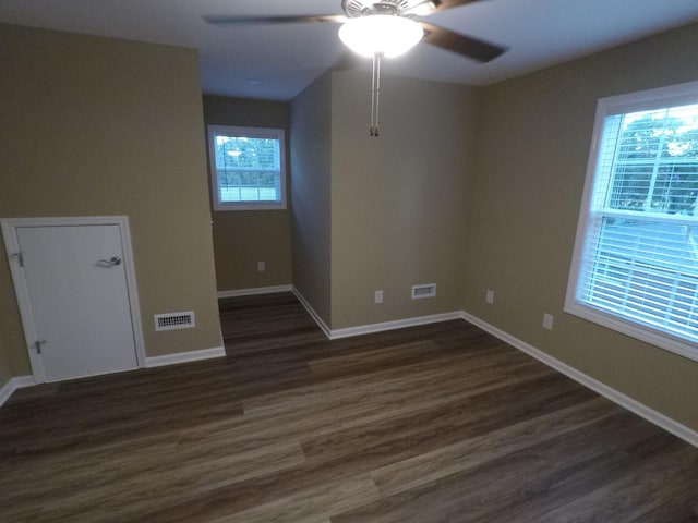 spare room featuring ceiling fan, dark wood-type flooring, visible vents, and baseboards