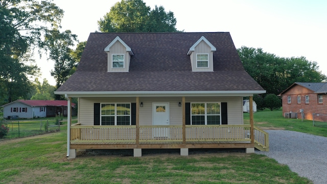 cape cod-style house featuring covered porch and a front lawn