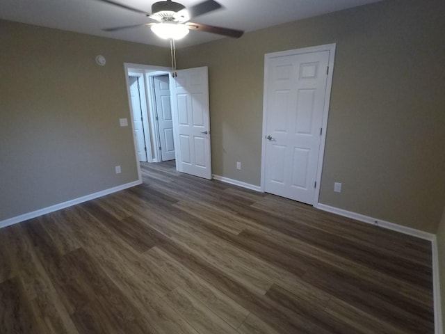 empty room featuring a ceiling fan, dark wood-style flooring, and baseboards