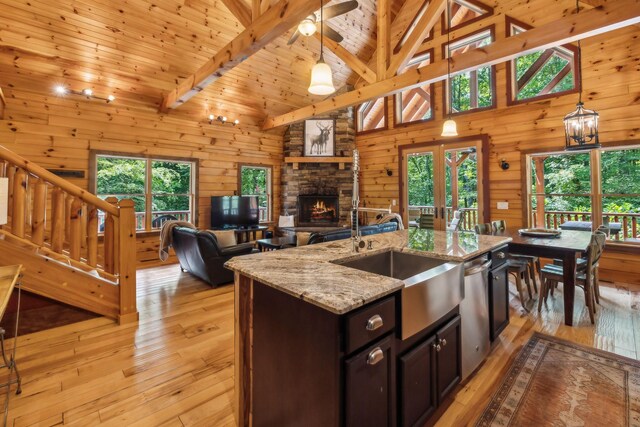 kitchen with a fireplace, light wood-type flooring, beam ceiling, dark brown cabinets, and hanging light fixtures