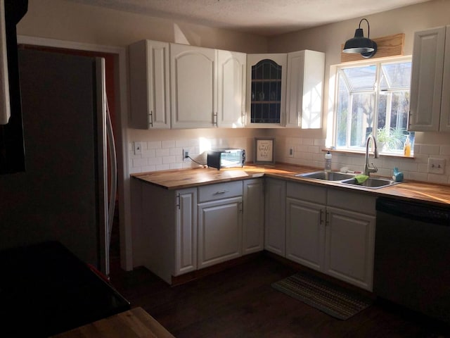 kitchen featuring fridge, butcher block countertops, white cabinets, dishwasher, and sink