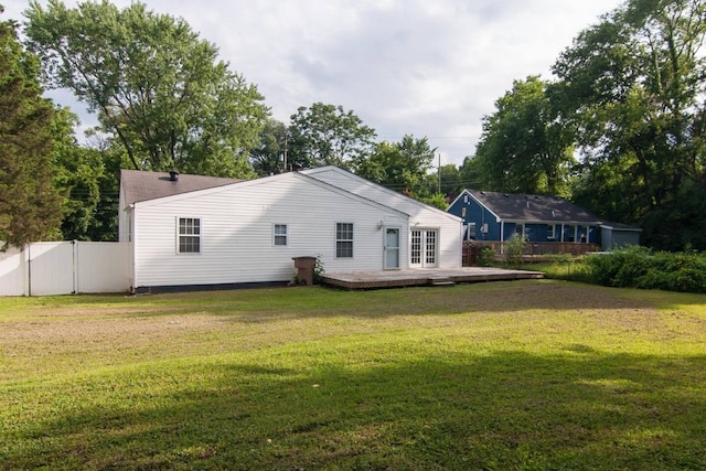 back of property with a wooden deck and a lawn