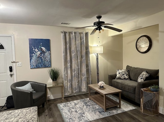 living room featuring ceiling fan and dark wood-type flooring