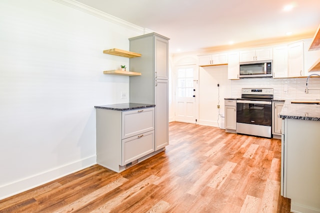 kitchen with backsplash, sink, ornamental molding, appliances with stainless steel finishes, and light hardwood / wood-style floors