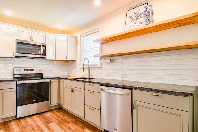 kitchen featuring decorative backsplash, dark stone countertops, appliances with stainless steel finishes, and light hardwood / wood-style floors