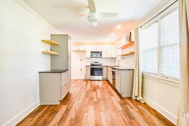 kitchen with backsplash, sink, light wood-type flooring, appliances with stainless steel finishes, and ceiling fan