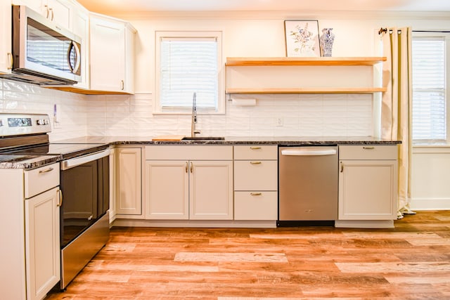 kitchen featuring dark stone counters, backsplash, light hardwood / wood-style floors, sink, and stainless steel appliances