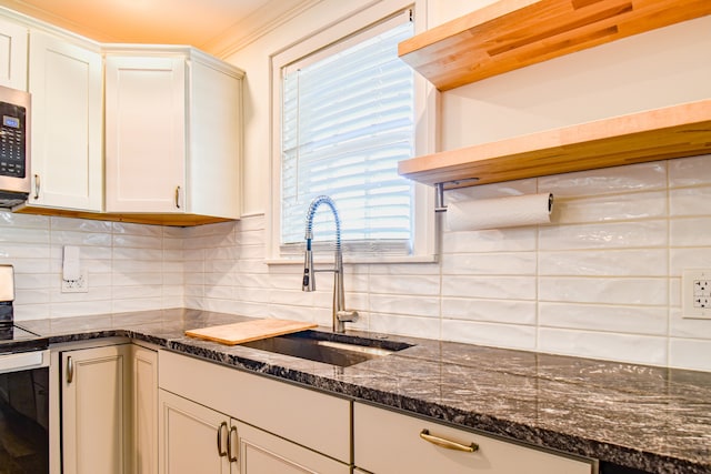 kitchen with stainless steel appliances, decorative backsplash, ornamental molding, sink, and dark stone counters