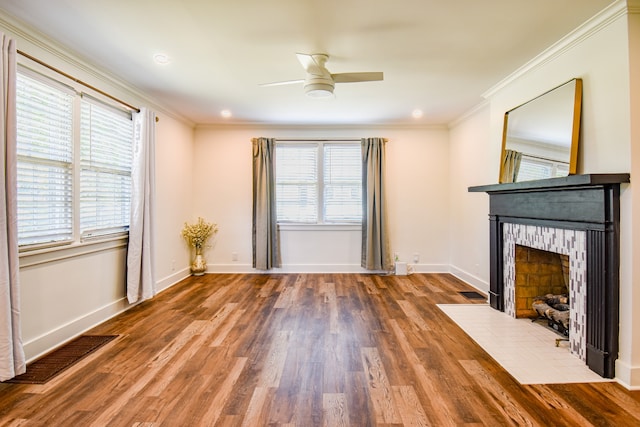 unfurnished living room with ceiling fan, a brick fireplace, crown molding, and wood-type flooring