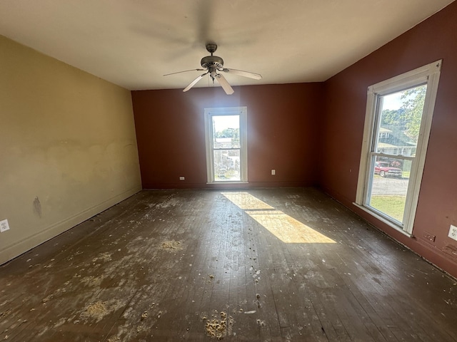 unfurnished room with dark wood finished floors, a ceiling fan, and baseboards