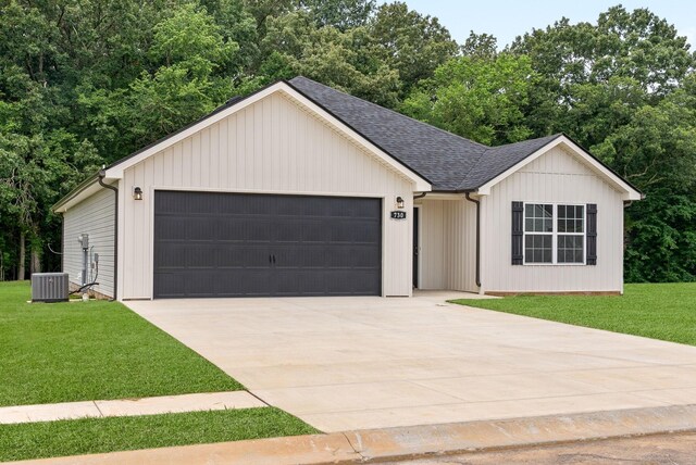 view of front of property with a garage, central AC unit, and a front yard