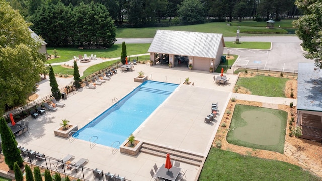 community pool with a patio, an outdoor fire pit, a lawn, and fence