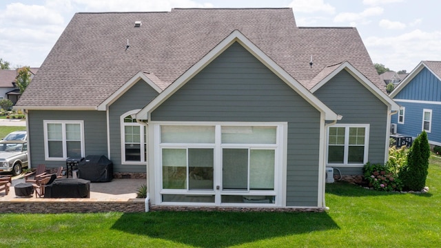 rear view of property with a patio, a yard, and roof with shingles