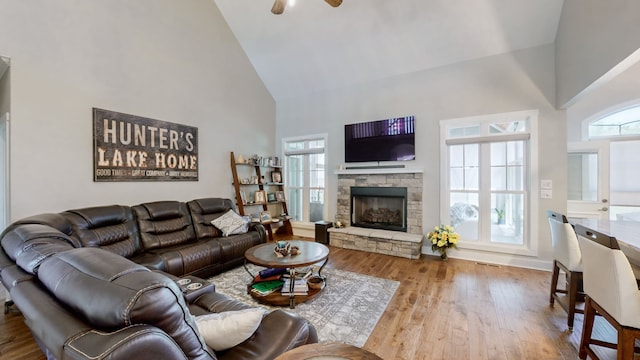 living room featuring ceiling fan, high vaulted ceiling, light hardwood / wood-style flooring, and a fireplace