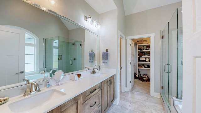 full bath featuring double vanity, a stall shower, a walk in closet, and a sink