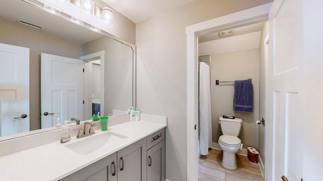 bathroom featuring visible vents, toilet, vanity, and baseboards