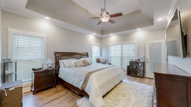 bedroom with ceiling fan, light wood-type flooring, crown molding, and a tray ceiling