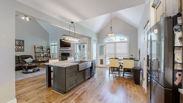 kitchen featuring appliances with stainless steel finishes, light hardwood / wood-style flooring, sink, light stone countertops, and a fireplace