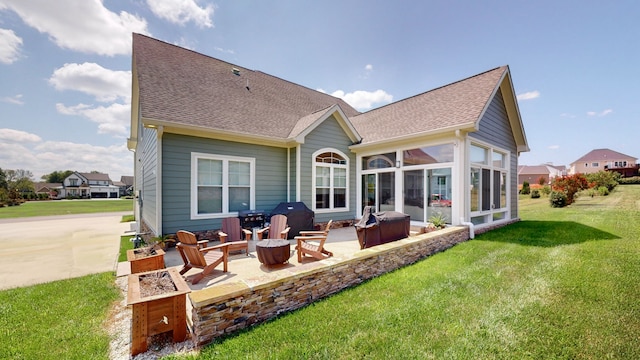 rear view of house with a yard, an outdoor fire pit, a sunroom, and a patio