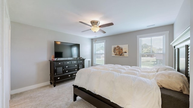 bedroom with a ceiling fan, visible vents, baseboards, and light carpet