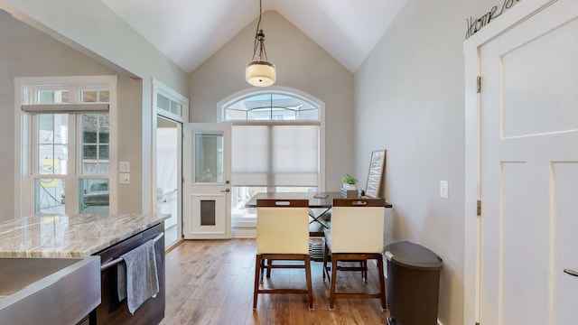 dining space with light wood-type flooring and high vaulted ceiling