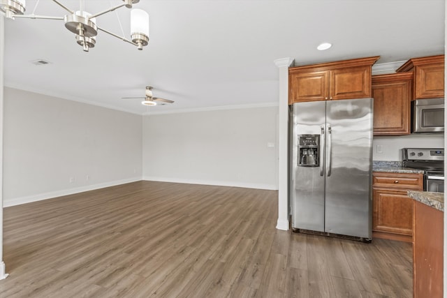 kitchen with ceiling fan with notable chandelier, appliances with stainless steel finishes, ornamental molding, and hardwood / wood-style floors