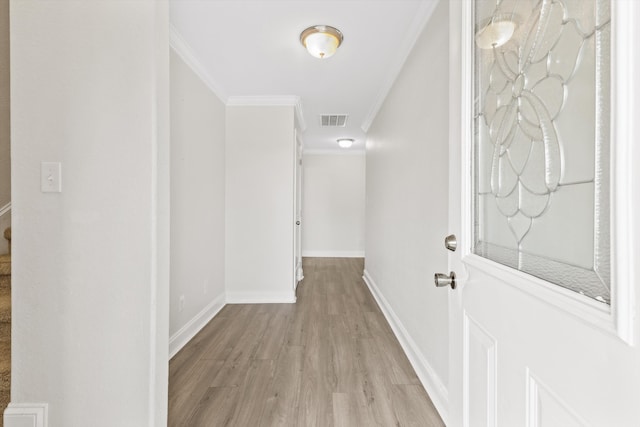 hallway with ornamental molding and light hardwood / wood-style floors