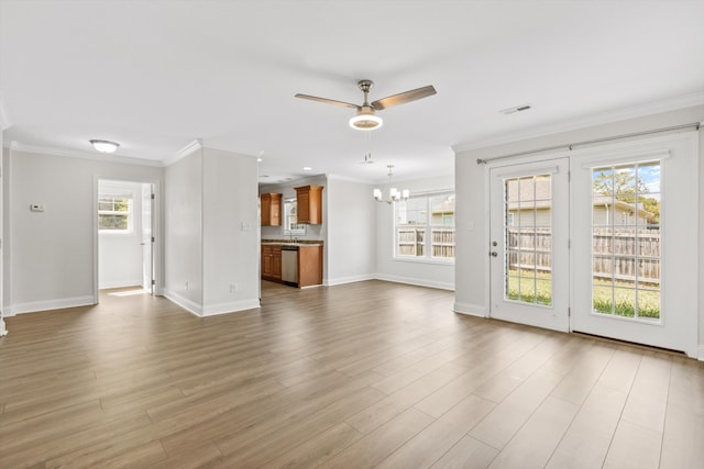 unfurnished living room featuring plenty of natural light, ornamental molding, ceiling fan with notable chandelier, and light hardwood / wood-style floors