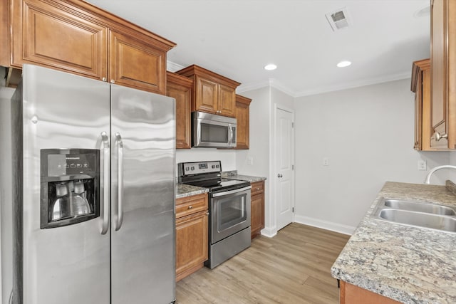 kitchen featuring crown molding, appliances with stainless steel finishes, light hardwood / wood-style flooring, and sink