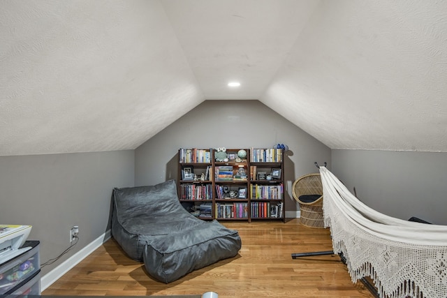 sitting room featuring light wood-type flooring, a textured ceiling, and lofted ceiling