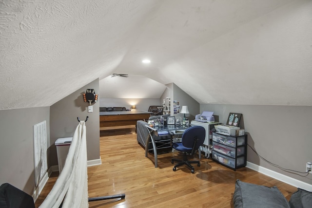 home office with a textured ceiling, lofted ceiling, and hardwood / wood-style floors