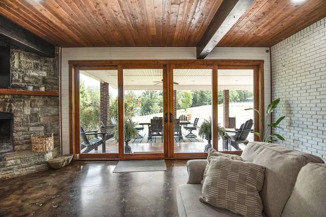 sunroom featuring wood ceiling, beam ceiling, a stone fireplace, and french doors