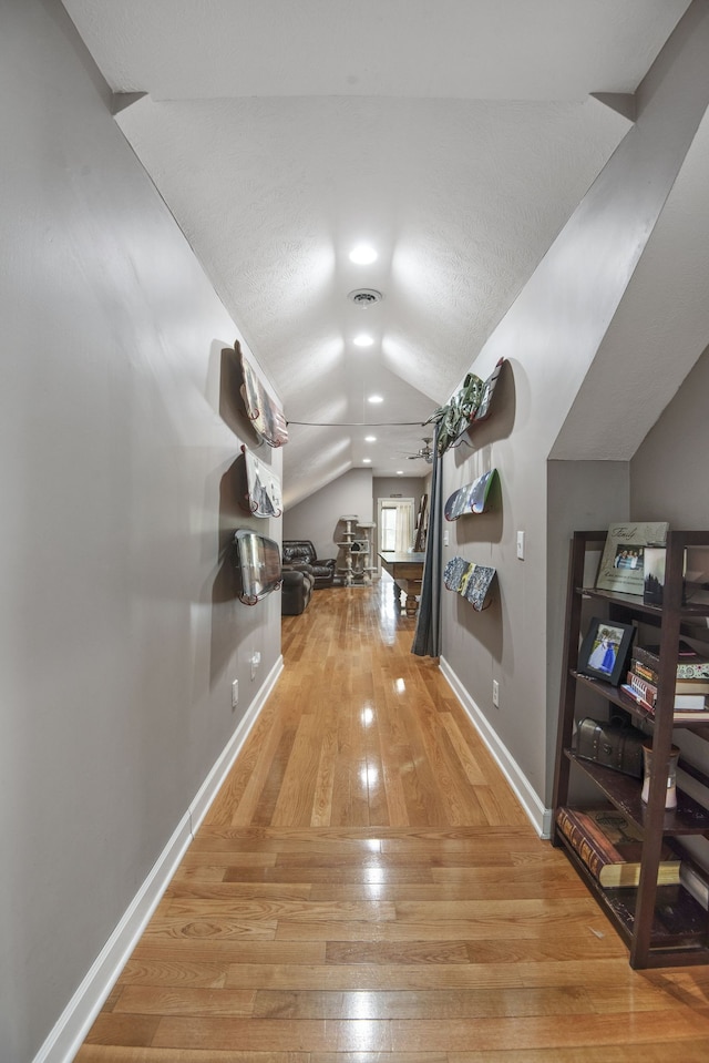 hall with vaulted ceiling and light hardwood / wood-style flooring