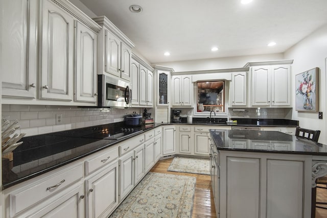 kitchen featuring a breakfast bar area, a center island, black electric stovetop, and tasteful backsplash