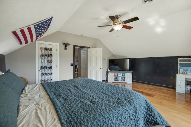 bedroom with ceiling fan, a closet, lofted ceiling, and light wood-type flooring