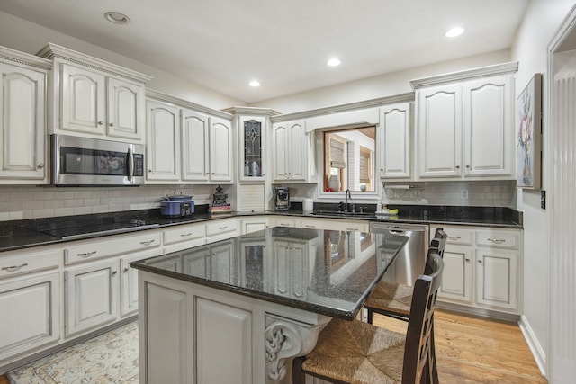 kitchen featuring backsplash, stainless steel appliances, light hardwood / wood-style floors, a kitchen breakfast bar, and a kitchen island