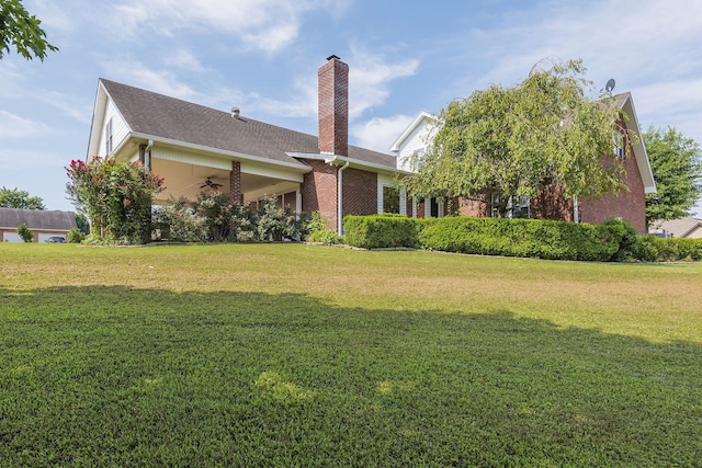 rear view of property featuring a lawn and ceiling fan