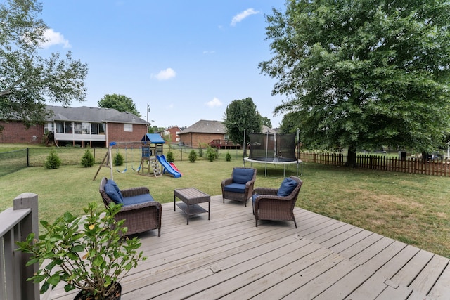 wooden deck featuring a yard, a trampoline, and a playground