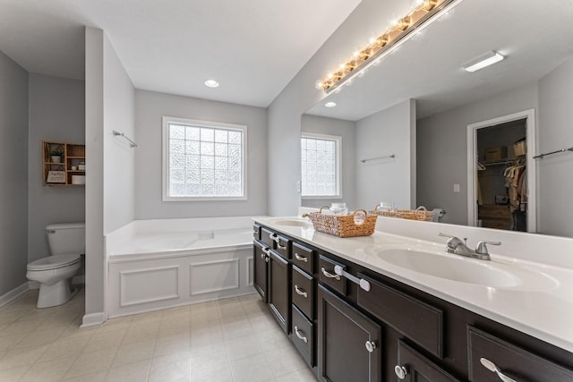 full bath featuring a sink, toilet, a walk in closet, and a bath