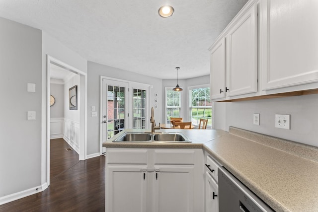 kitchen featuring dark wood-style floors, light countertops, hanging light fixtures, white cabinetry, and a sink