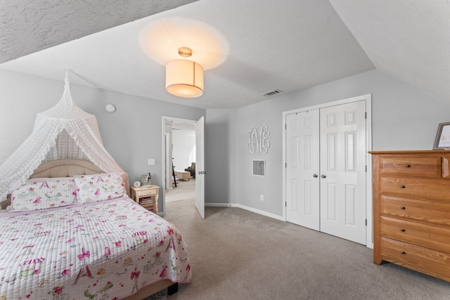 bedroom with a textured ceiling, carpet floors, lofted ceiling, and a closet