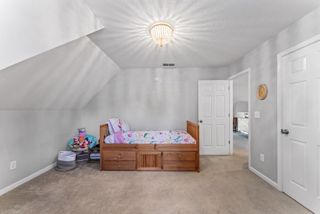 bedroom featuring vaulted ceiling, a textured ceiling, and light carpet