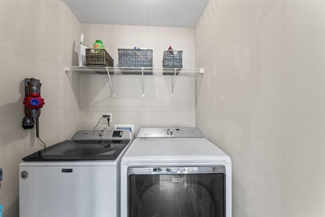 washroom with a textured ceiling and separate washer and dryer