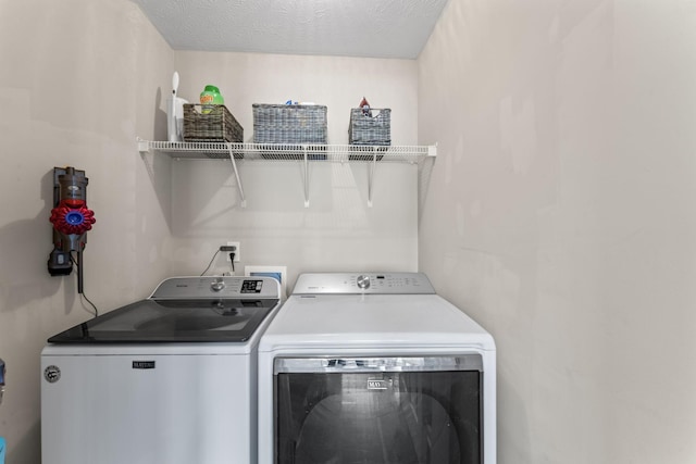 clothes washing area featuring laundry area, washer and clothes dryer, and a textured ceiling