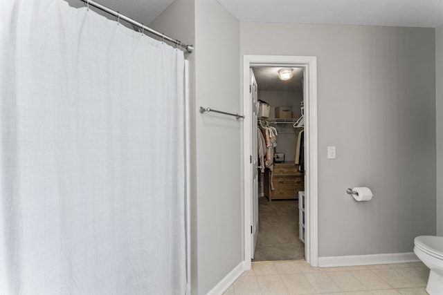 bathroom featuring tile patterned flooring, walk in shower, and toilet